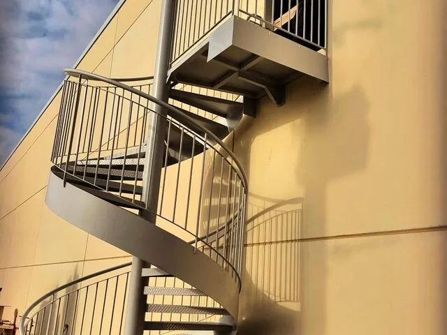 Escalier hélicoïdal gris sur façade d’un bâtiment professionnel