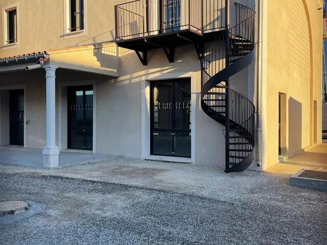 Escalier hélicoïdal noir en façade d’un bâtiment en pierre dorée