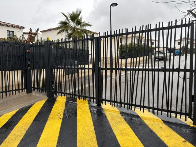 Portail noir fermé avec marquage au sol de sécurité jaune et noir