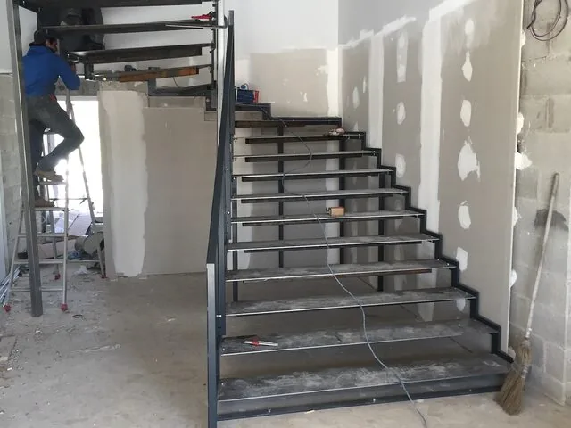 Escalier métallique droit intérieur en cours de pose, structure acier apparente