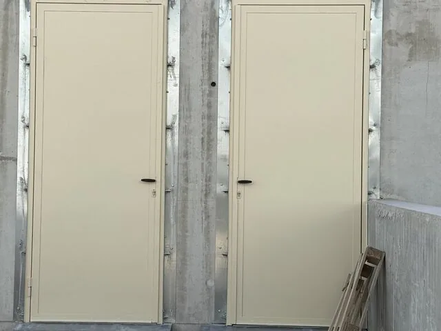 Deux portes techniques beiges posées en façade brute avant finition